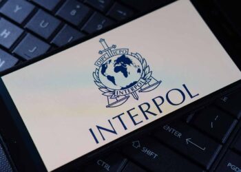 Interpol logo on phone, resting on a keyboard.