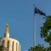 Oregon state capitol building with state flag and blue sky.