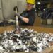 Worker at an e-scrap facility raking shredded material.