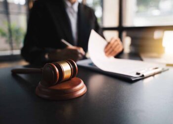 Lawyer with gavel, working on documents at a desk.
