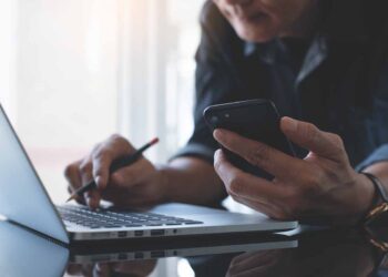 Person using a cell phone and laptop.