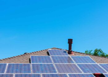 Solar panels on a residential roof with blue sky above.